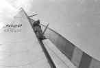 man standing in mast of sailing boat           